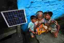 A solar PV panel powers an electronic device entertaining an elderly woman and children in West Bengal, India. Supriya Biswas