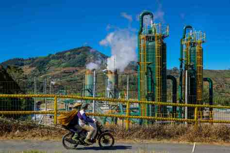 A motorcyclist and his passenger watch steam rise out of the Dieng Plateau’s geothermal power plant in Java, Indonesia. Bambang Wirawan